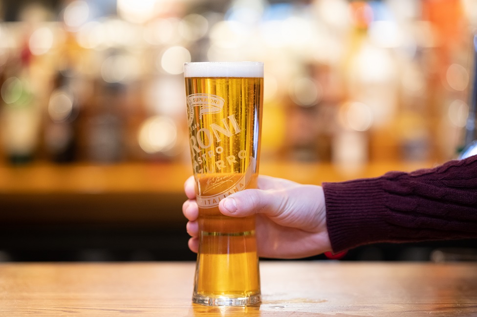 A man holding a pint indoors